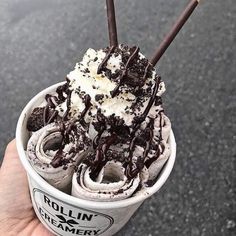 an ice cream sundae with chocolate and whipped cream in a paper cup on the street