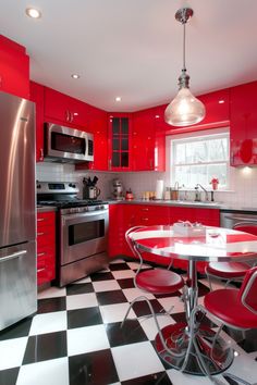 a kitchen with red cabinets and black and white checkered flooring