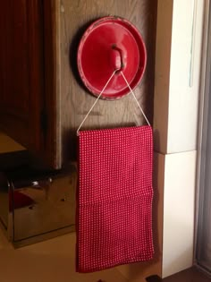 a red piece of cloth hanging on a wall next to a door with a metal object attached to it