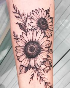 a sunflower tattoo on the leg with black and white flowers in front of it