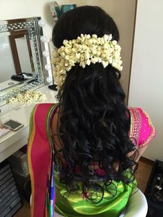 the back of a woman's head with flowers in her hair, sitting on a chair