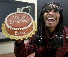 a man with dreadlocks holding up a birthday cake