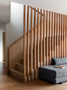 a gray couch sitting next to a wooden stair case