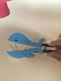 a person cutting out a paper cutout of a blue whale with a man on it