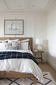 a bed with white and blue comforter in a bedroom next to a painting on the wall