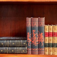 three books sitting on top of a wooden shelf next to each other in front of a bookcase