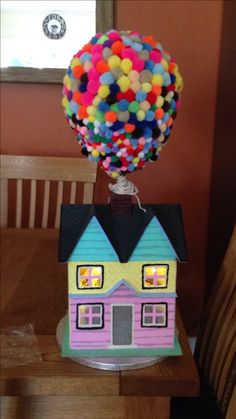 a house with balloons on top of it in the middle of a dining room table