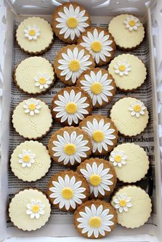 some cookies with white and yellow flowers on top of each other in a cardboard box