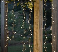 some lights that are hanging from the side of a wooden structure with vines on it