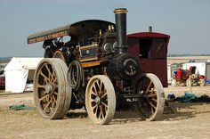 an old steam engine sitting on top of a dirt field