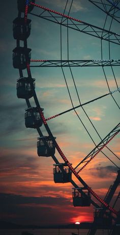 a ferris wheel with the sun setting in the background