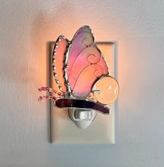 a light switch with a pink butterfly on it's side and a flower in the middle