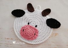 a crocheted cow head is shown on a white tablecloth with brown and black ears