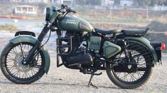 a green motorcycle parked on top of a gravel road