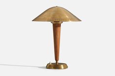 an antique brass table lamp with a wooden base on a plain white background the light is turned off