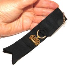 An Edwardian black ribbon watch fob with a tested 14 K ornate seal. The ribbon is folded over and sewn onto a gold-filled hanger which is attached to a gold-filled watch hook via a short chain. The gold seal is hanging on a hollow ring sewn into the fold of the ribbon. The ornate seal has a scrolled top and engraved initials on the bottom -EAC. Everything is in excellent condition. The total length of the fob, from the hook to the end of the ribbon is 18 cm. The seal itself is 2.6 cm wide. A good accessory for the collector of antique watches! Classic Formal Jewelry With Brass Hardware, Elegant Gold Jewelry For Black Tie Event, Elegant Gold Jewelry For Black Tie, Gold Ribbon Jewelry For Formal Occasions, Elegant Black Jewelry With Gold Clasp, Black Jewelry With Gold Clasp For Formal Occasions, Formal Black Jewelry With Black Ribbon, Vintage Gold Jewelry With Ribbon, Hollow Ring