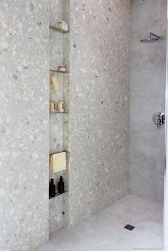 a bathroom with a walk in shower next to a white tiled wall