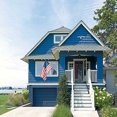 a blue house with an american flag on the front door and steps leading up to it