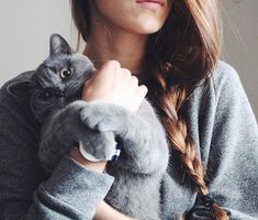 a woman holding a gray cat in her arms