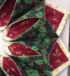 a close up of a red and green quilted umbrella with holly leaves on it