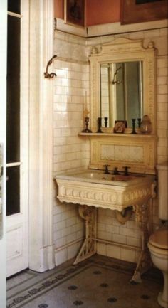 a bathroom with a toilet, sink and mirror in it's corner area next to a doorway