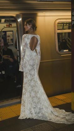 a woman in a white dress standing on a subway platform with her back to the camera