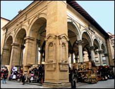 an outdoor market with people standing around and looking at the items on display in front of it