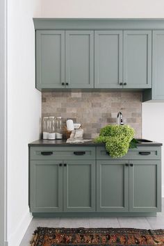 a kitchen with green cabinets and a rug on the floor