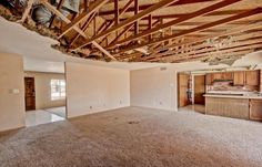 an empty kitchen and living room in a house with wood framing on the ceiling is being remodeled