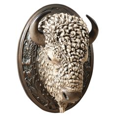 an animal head mounted on the side of a metal wall mount with curly hair and horns