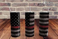 three black and red striped tumblers with straws in them on a wooden table