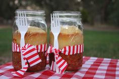 two mason jars filled with food sitting on top of a red and white checkered table cloth