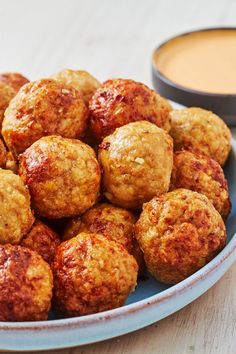 a plate filled with meatballs next to a bowl of dipping sauce on the side