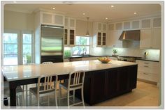 a large kitchen with white cabinets and stainless steel refrigerator freezer next to an island