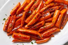 a white plate topped with sliced carrots covered in ketchup and parsley