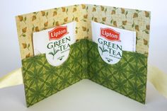 an open book with two tea bags in the front and one green tea bag on the back