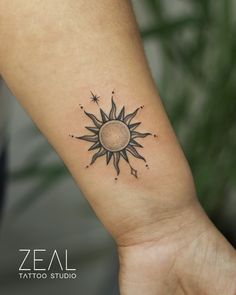 a small sun tattoo on the wrist with stars around it and an arrow in the middle