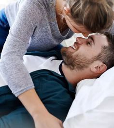 a man and woman laying in bed with their noses touching each other's foreheads