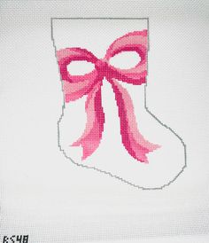 a cross stitch christmas stocking with a pink bow on it's side,