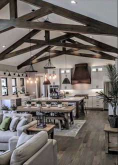 a large open concept kitchen and living room with wood beams on the ceiling, white couches in front of an l - shaped dining table