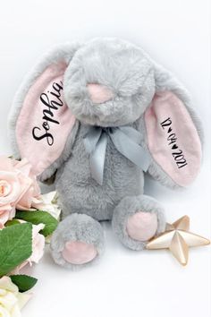 a stuffed rabbit sitting next to flowers on a white background with the words happy birthday written on it