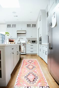 a kitchen with white cabinets and an area rug on the floor in front of it