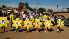 children holding up signs in the shape of flowers with words brasil on them and people standing around