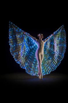 a woman with wings on her body is posing for the camera in front of a dark background