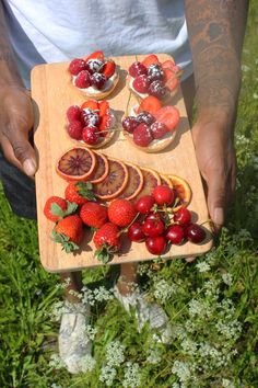 a person holding a wooden tray with fruit on top of it in their hands,