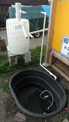 a black tub sitting in the grass next to a fence