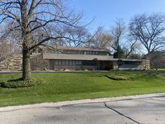 a large house sitting on top of a lush green field next to a tree in front of it