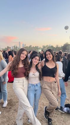 three girls posing for the camera in front of a crowd