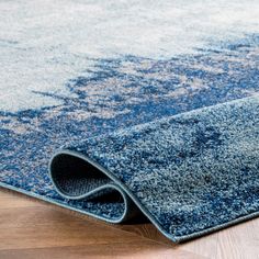 a blue area rug on the floor with a wooden floor and wood floors in the background