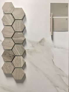 a white marble counter top next to a gray tile wall with some tiles on it